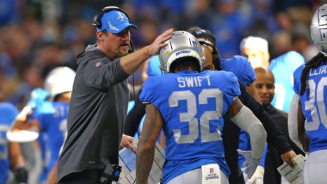 American football manager talks with his player after he was replaced during a match