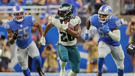 The American football player runs the ball while being pursued by the players of the opposing team