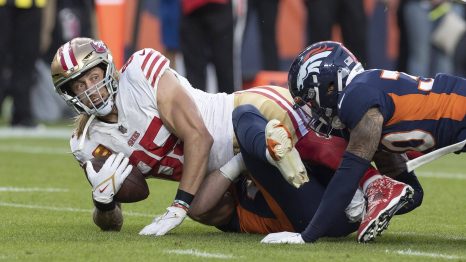 American football player with the ball in his arms goes down in a heap