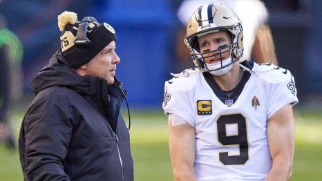 American football player talks with his manager on the field after a match