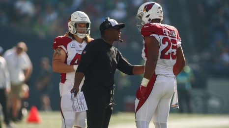 American football players talk with their manager on the field during a timeout