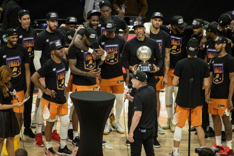 Basketball players celebrate the cup winning and a reporter with microphone congrats them